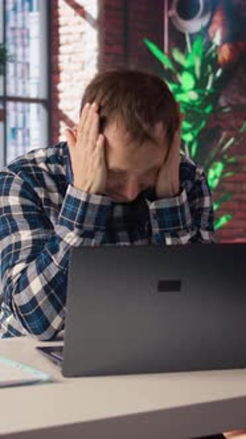 Man Working on Laptop in Office, Tired and Stressed
