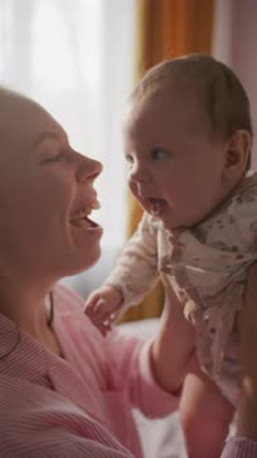 Woman holding baby in sunlight by the window