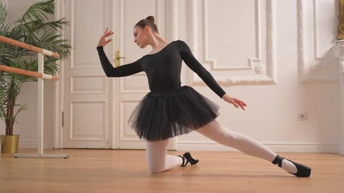 Ballet Dancer Kneels and Stretches in Elegant Studio