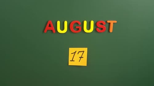 Hand sticking a sticker 17 August calendar day on school board. 17 date of august. Seventeenth day