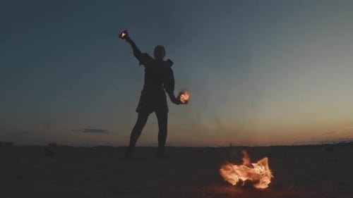 Performer Juggling Fire on Beach at Sunset