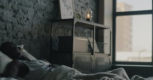 Young Man Wakes and Stretches in Urban Bedroom