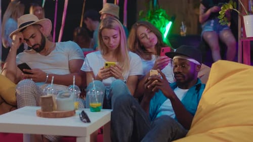 Friends Checking Phones on a Night Out