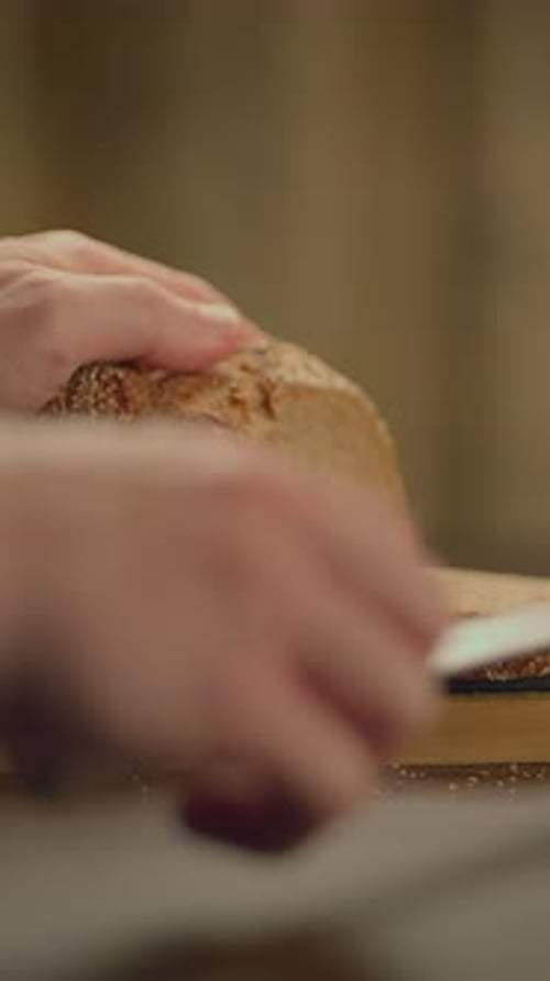 Person slicing loaf of bread in kitchen