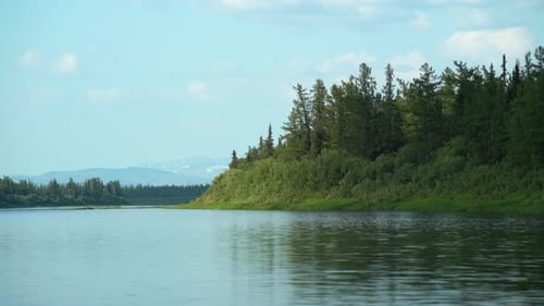 Green Forest on a Hill on a Lake Against a Blue Sky