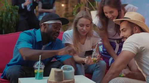 Friends Laughing and Watching Phone at Outdoor Party