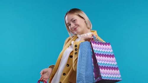 Happy Woman Holding Shopping Bags on Blue Background