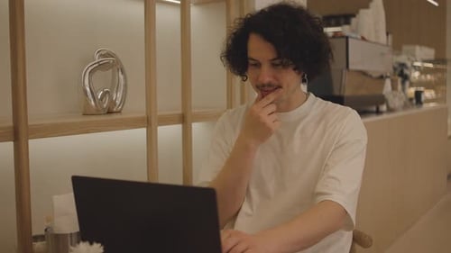 Successful Young Man Using Laptop and Drinks Coffee While Sitting in Cafe in the City Centre