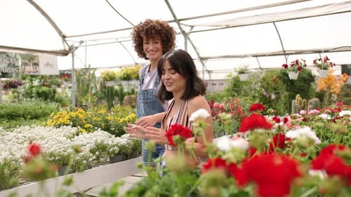 Two Friends Walking Through Flower Filled Greenhouse