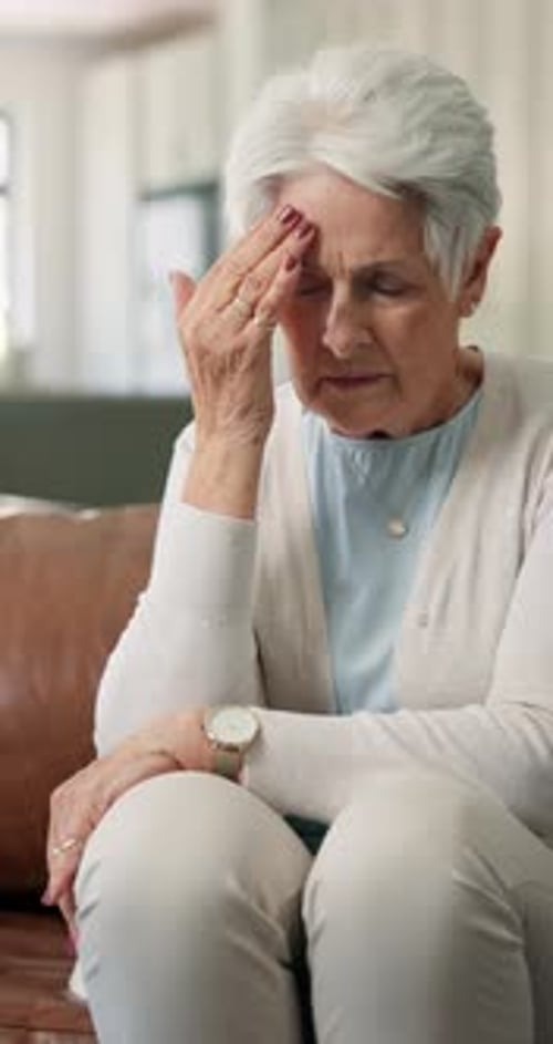 Senior, stress and woman with headache on sofa from hypertension, discomfort and chronic disease