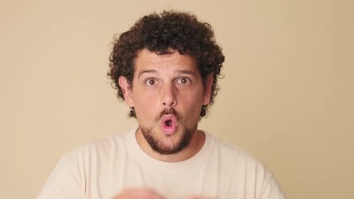 Close up, shocked man looking at the camera with big eyes, says wow, on beige background