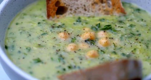 Vegetable Soup in 4K high resolution. Rotating bowl with toasted bread. Green healthy lunch shot wit