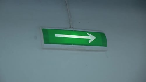 Glowing green arrow on wall. Arrow on green background lights up to indicate exit