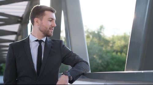 Bearded Businessman Checking Watch Outdoors on Sunny Day