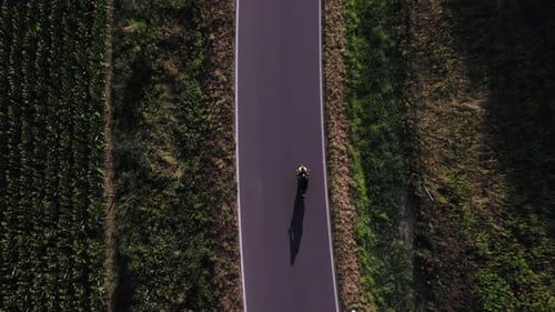 Man Driving Modern Sport Motorcycle on Countryside Asphalt Road at Sunset - Top-down view from drone