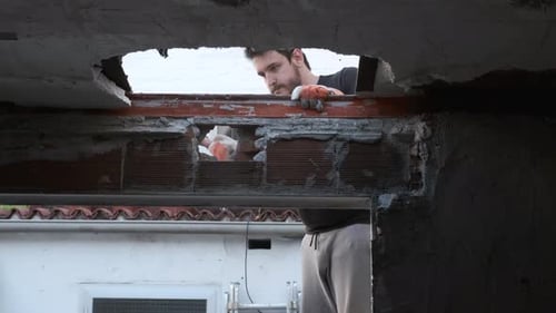 Young man pulling the ceiling of a house down.