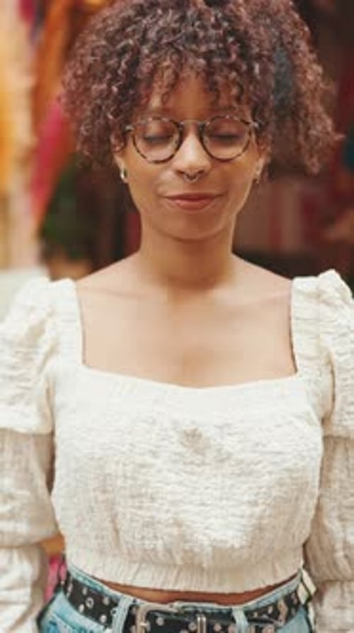 Closeup, woman in glasses stands next to a flower shop and looks at the camera and smiling