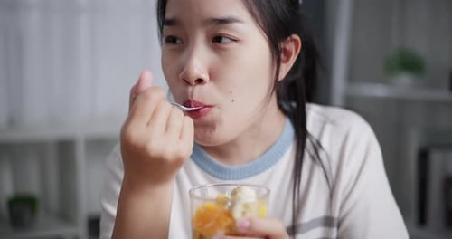 Woman Eats Fruit and Yogurt Snack Indoors