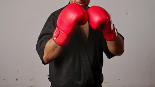 Man Practicing Boxing with Red Gloves and Gi