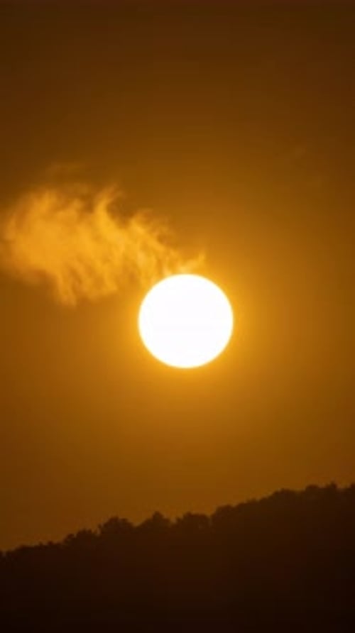 Zeitraffer eines dramatisch Sonnenuntergangs mit orangefarbenem Himmel an einem sonnigen Tag.