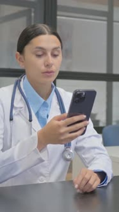 Woman Doctor Using Cellphone in Clinic Setting