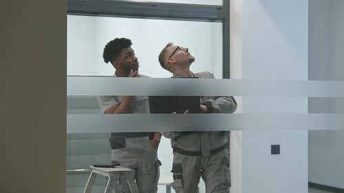 Multi Ethnic Installers in Uniform Sets Up Internet in Office Room Using Laptop