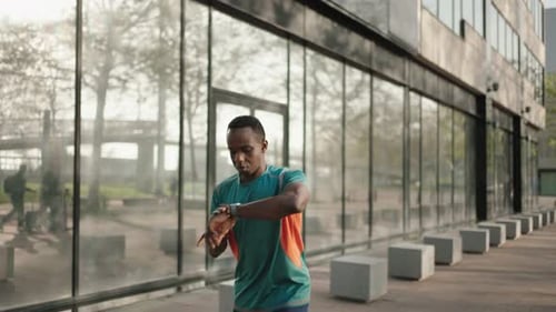 Black Man Checking Fitness Performance on Smartwatch App Running in the City