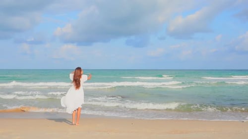 Slow-motion of Woman walking and jumping barefoot on the beach towards the sea in summer then she s