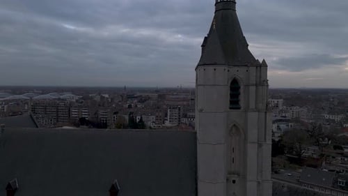 Drone shot of a church top in a city center on a cloudy day revealing the church.