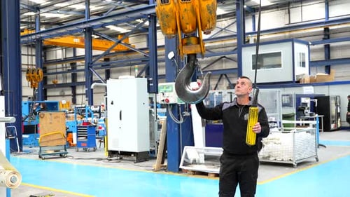 Homme contrôlant le crochet d'une grue industrielle