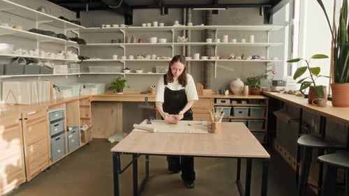 Woman Working with Clay in Well-Lit Pottery Workshop