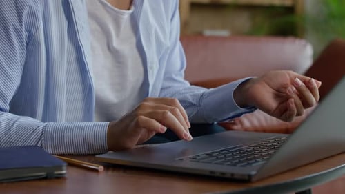 Woman Uses Laptop Touchpad Indoors at Wooden Table
