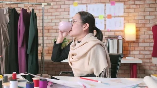 Asiatische Modedesignerin arbeitet nach Ideen und zeichnet Skizzen für ein Kleidungsdesign.