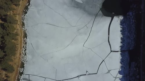 Aerial top view of a cracked frozen lake due to global warming
