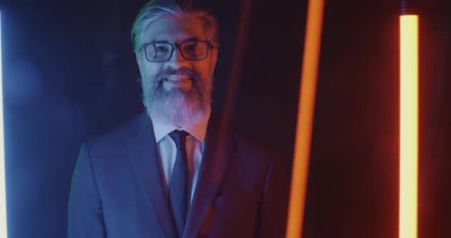 Slow Motion Portrait of Mature Businessman Smiling Looking at Camera in Neon Illuminated Space