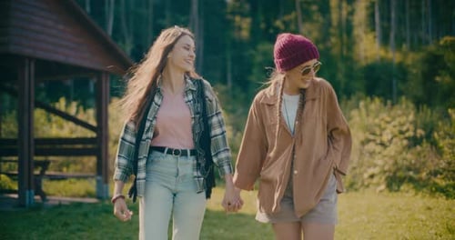 Happy Female Friends Holding Hands While Waking In Forest