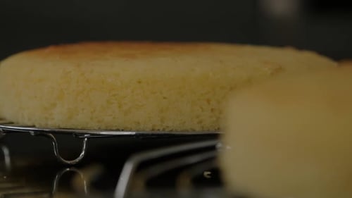A deliciously fluffy sponge cake sits on a cooling rack after baking.