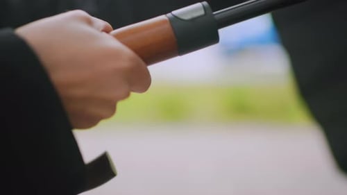 Close Up of Hand Holding Wooden Handle of Umbrella Outdoors During Rainy Day