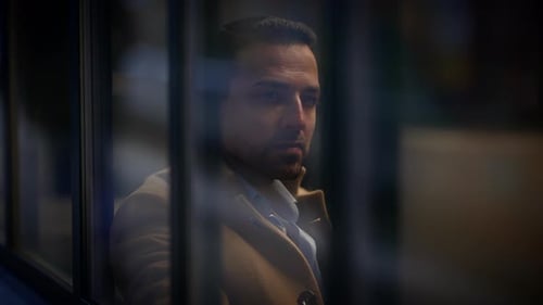 Thoughtful Man Looking Out City Window at Night