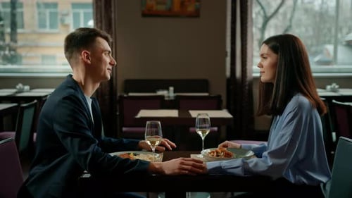 Date in the hotel restaurant dinner man and woman drink white wine in glasses and taste food