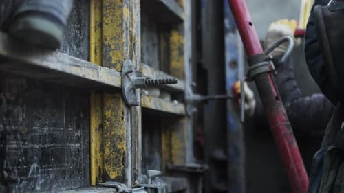 L'ouvrier ajuste la connexion au coffrage à l'aide d'un marteau