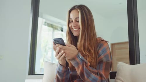 Smiling Woman Using Smartphone Inside Modern Apartment