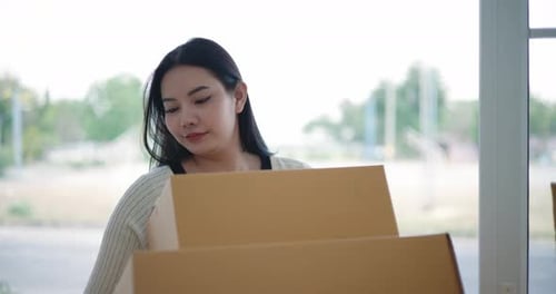Woman Moving Cardboard Boxes into New Home
