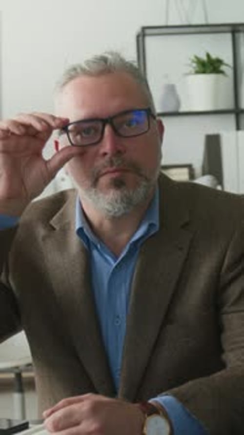 Portrait of Mature Businessman Posing with Smile at Office Desk