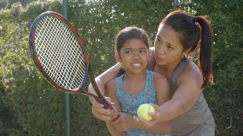 Child Learning Tennis with Instructor Outdoors