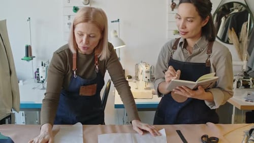 Middle-Aged Female Tailor Training Young Apprentice in Workshop