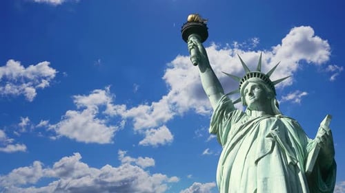 Statue of Liberty in New York against the backdrop of clouds on a sunny clear day, timelapse.