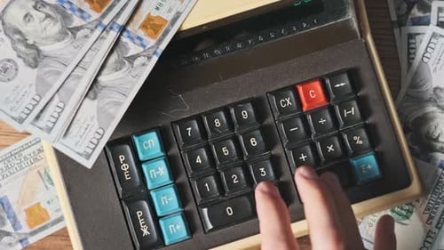 Top View Counting on Old Vintage Calculator Surrounded By Dollar Bills CloseUp