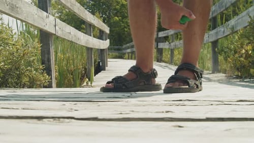 Man Applies Mosquito Spray By the Lake on a Sunny Morning