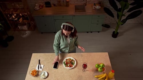 Happy Woman Dancing in Her Kitchen with Salad